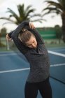 Молодая женщина выполняет упражнения на растяжку на теннисном корте — стоковое фото