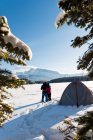 Paar Touristen stehen zusammen in einer verschneiten Landschaft vor einem Zelt. — Stockfoto