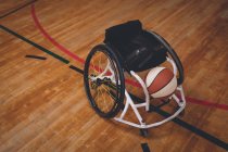 Fauteuil roulant vide et balle de basket dans le court — Photo de stock