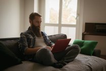 Homem usando laptop no sofá na sala de estar — Fotografia de Stock