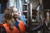 Female worker checking boxes in factory warehouse — Stock Photo