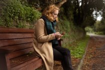 Junge Frau benutzt Handy im Park — Stockfoto