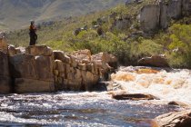Kajakfahrerin steht auf Felsen in Flussnähe. — Stockfoto
