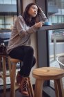 Задумчивая женщина пьет кофе за столом в столовой — стоковое фото