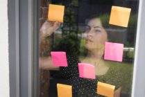 Executivo feminino olhando notas pegajosas no escritório — Fotografia de Stock