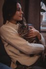 Мрійлива жінка обіймає свого домашнього кота вдома — стокове фото