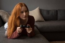 Mujer joven jugando videojuegos en casa - foto de stock