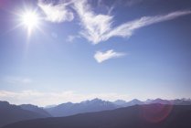 Soleil se levant sur une chaîne de montagnes rocheuses avec des nuages passant par — Photo de stock