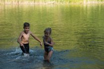 Siblings playing in river on a sunny day — Stock Photo