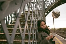 Красива жінка використовує мобільний телефон у залізничній формі — стокове фото