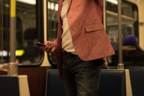 Parte centrale dell'uomo che utilizza il telefono cellulare mentre viaggia in treno — Foto stock