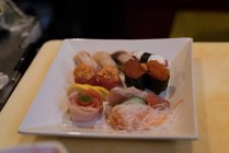 Table de sushi arrangée dans un restaurant par une journée ensoleillée — Photo de stock