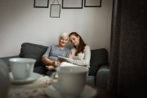 Grandmother and granddaughter using digital tablet in living room at home — Stock Photo