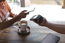 Дівчина-підліток робить оплату через мобільний телефон в ресторані — стокове фото