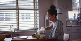 Woman pouring milk into bowl at home — Stock Photo