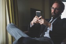 Businessman using mobile phone in hotel room — Stock Photo
