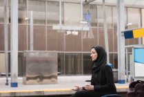 Mujer en hijab usando teléfono móvil en la estación de tren - foto de stock