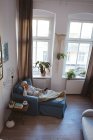 Висока кут зору старший жінка розслабляючий на дивані з смарт-телефону, слухати музику на дому — стокове фото