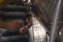 Средняя часть работника мужского пола проверяет давление джина на спиртовом заводе — стоковое фото