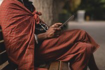 Seção média do homem maasai em roupas tradicionais usando telefone celular — Fotografia de Stock