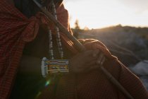 Mid section of maasai man in traditional clothing sitting with stick — Stock Photo