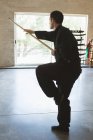 Combattant de kung fu pratiquant avec un long poteau dans un studio de fitness . — Photo de stock
