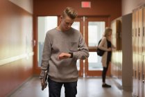 Підлітковий хлопчик перевіряє час на смарт-годиннику в коридорі — стокове фото
