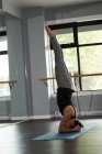 Mujer practicando yoga en colchoneta de ejercicio en gimnasio . - foto de stock