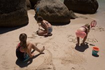 Irmãos brincando na areia na praia em um dia ensolarado — Fotografia de Stock