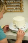 Gros plan de la femme préparant un gâteau en boulangerie — Photo de stock