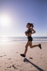 Fit femme jogging dans la plage de sable fin au crépuscule . — Photo de stock