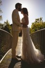 Noiva e noivo beijando na passarela no jardim em um dia ensolarado — Fotografia de Stock