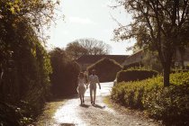 Braut und Bräutigam gehen an einem sonnigen Tag Hand in Hand im Garten — Stockfoto