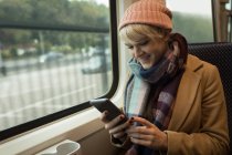 Mujer sonriente usando el teléfono móvil mientras viaja en autobús - foto de stock