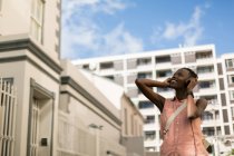 Женщина слушает музыку на наушниках на городской улице — стоковое фото