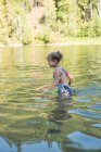 Glückliches Mädchen spielt an einem sonnigen Tag im Fluss — Stockfoto