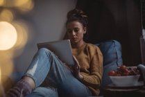 Mujer concentrada usando tableta digital en casa - foto de stock