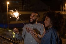 Smiling couple playing with sparkles at night — Stock Photo