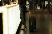 Donna d'affari in piedi alla reception con il suo bagaglio in hotel — Foto stock