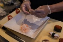 Koch rollt ausgerolltes Sushi auf Schneidebrett — Stockfoto