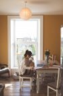 Jovem mulher tomando café enquanto trabalhava em casa — Fotografia de Stock