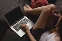 Жінка використовує ноутбук, маючи каву вдома — стокове фото