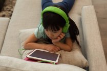 Frau mit Kopfhörer nutzt digitales Tablet zu Hause — Stockfoto