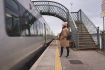 Заднього вигляду жінка чекає поїзда в залізничному вокзалі — стокове фото