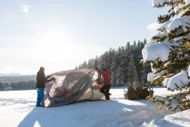 Couple pitching tent in snowy landscape during winter. — Stock Photo