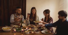 Amici brindare vino mentre si mangia a tavola — Foto stock