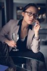Женщина разговаривает по мобильному телефону за бокалом вина — стоковое фото