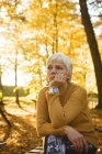 Задумчивая пожилая женщина сидит в парке в солнечный день — стоковое фото