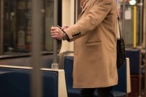 Средняя часть человека с помощью мобильного телефона во время поездов — стоковое фото