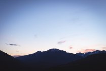Сонце за скелястим гірським хребтом з хмарами, що проходять повз — стокове фото